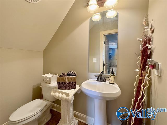 bathroom with toilet and lofted ceiling