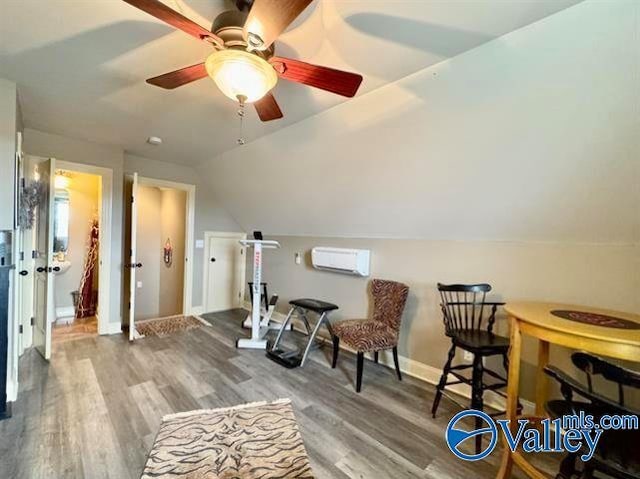 living area featuring hardwood / wood-style flooring, ceiling fan, lofted ceiling, and an AC wall unit