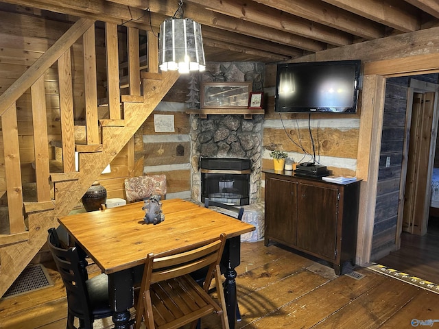 dining room featuring wood-type flooring, visible vents, and a stone fireplace