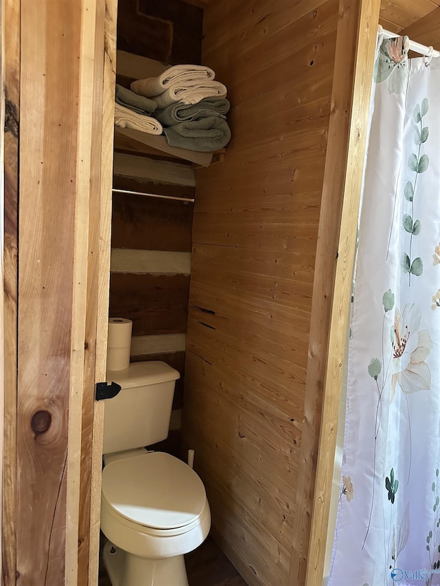 bathroom featuring toilet and wood walls