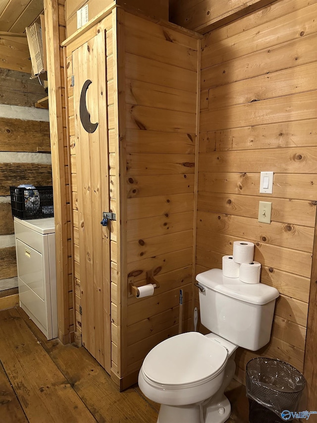 bathroom featuring wood walls, washer / dryer, and hardwood / wood-style flooring