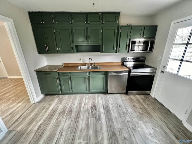 kitchen featuring stainless steel appliances, light hardwood / wood-style floors, green cabinets, and sink