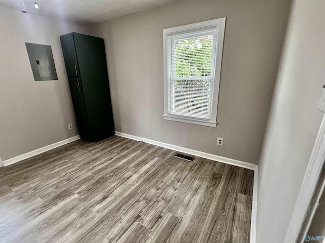 spare room with electric panel and light hardwood / wood-style flooring