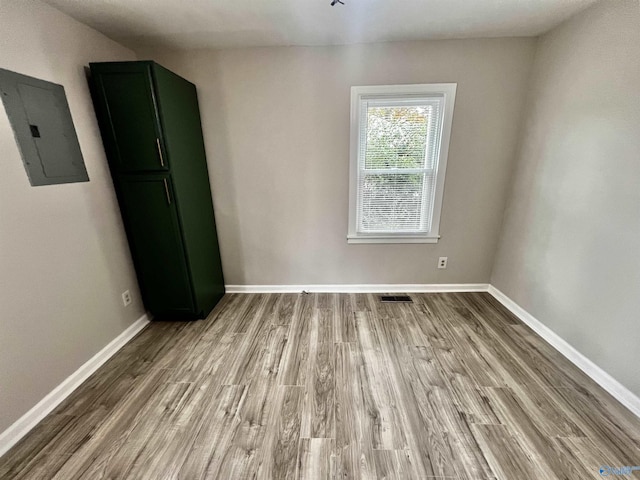 unfurnished room featuring electric panel and wood-type flooring