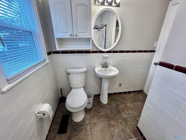 bathroom with sink, toilet, and tile walls