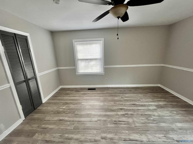 unfurnished bedroom with hardwood / wood-style floors, ceiling fan, and a closet