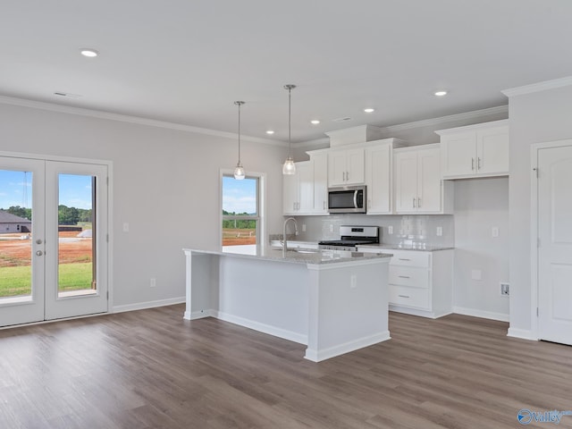 kitchen featuring white cabinets, appliances with stainless steel finishes, wood finished floors, a sink, and backsplash