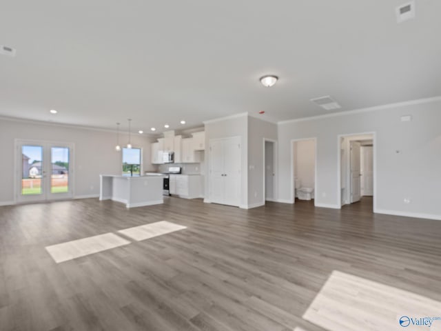unfurnished living room with crown molding, wood finished floors, and baseboards