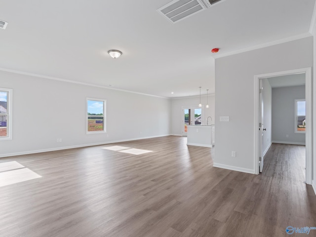unfurnished living room featuring ornamental molding, visible vents, plenty of natural light, and wood finished floors