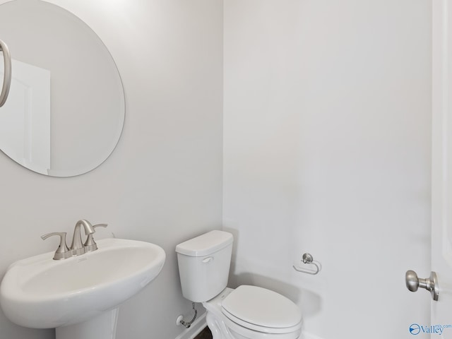 bathroom with toilet, a sink, and baseboards