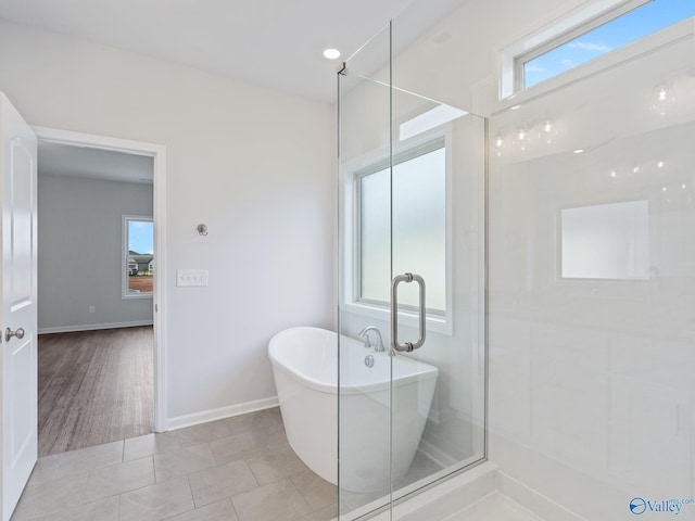 bathroom with tile patterned floors, a wealth of natural light, a freestanding bath, and baseboards