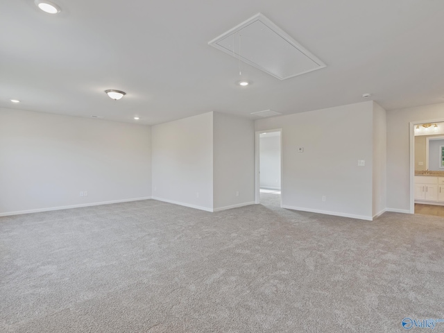 carpeted empty room featuring attic access, baseboards, and recessed lighting