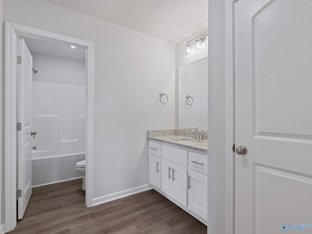 bathroom with shower / bathtub combination, vanity, toilet, wood finished floors, and baseboards