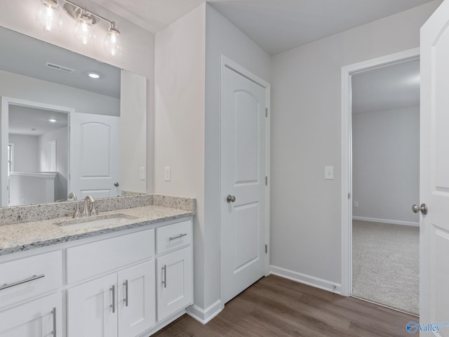 bathroom featuring wood finished floors, vanity, baseboards, and visible vents