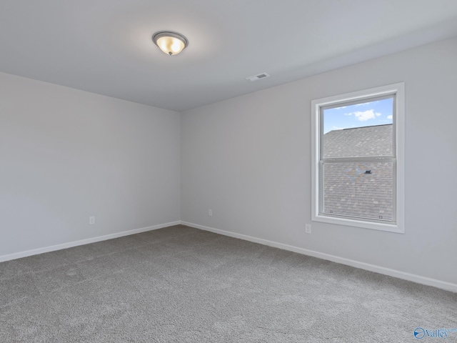 carpeted spare room featuring visible vents and baseboards
