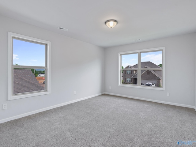 carpeted spare room featuring visible vents and baseboards