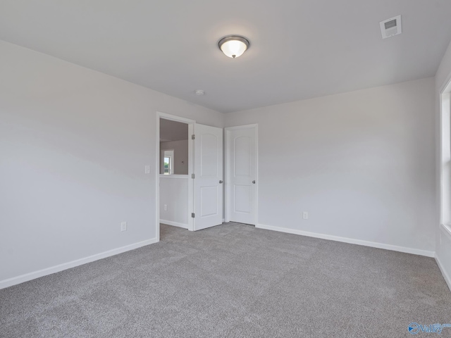 unfurnished room with visible vents, baseboards, and carpet floors