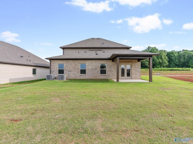 rear view of house with a patio, brick siding, central air condition unit, and a lawn