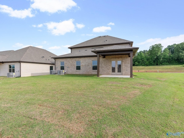 rear view of house featuring cooling unit, brick siding, and a lawn