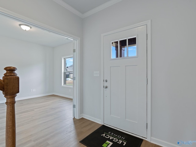 foyer entrance with crown molding, light wood-style flooring, and baseboards