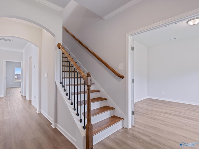staircase featuring ornamental molding, visible vents, arched walkways, and wood finished floors