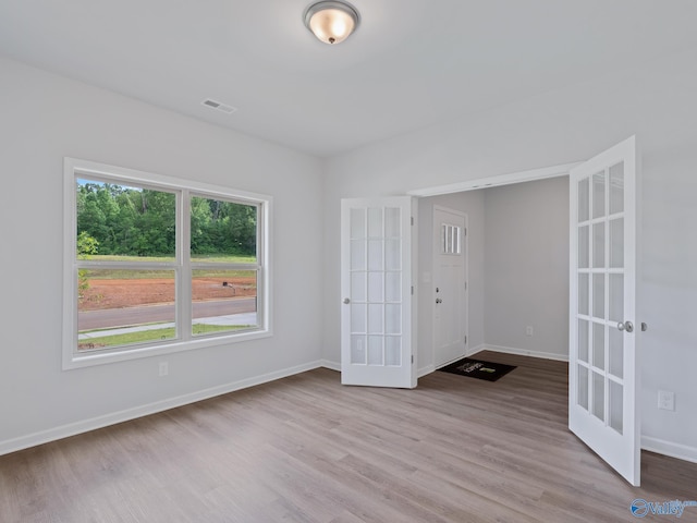 empty room with french doors, baseboards, visible vents, and wood finished floors
