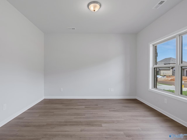 empty room with visible vents, baseboards, and wood finished floors