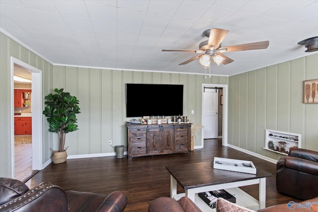living room featuring a ceiling fan, crown molding, baseboards, and wood finished floors