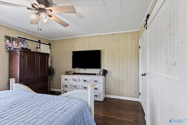 bedroom featuring ornamental molding, baseboards, a barn door, ceiling fan, and wood finished floors