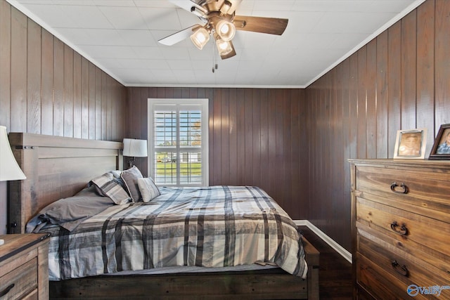 bedroom featuring crown molding, wooden walls, and ceiling fan
