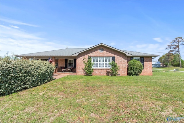 ranch-style home featuring brick siding, a front lawn, and metal roof