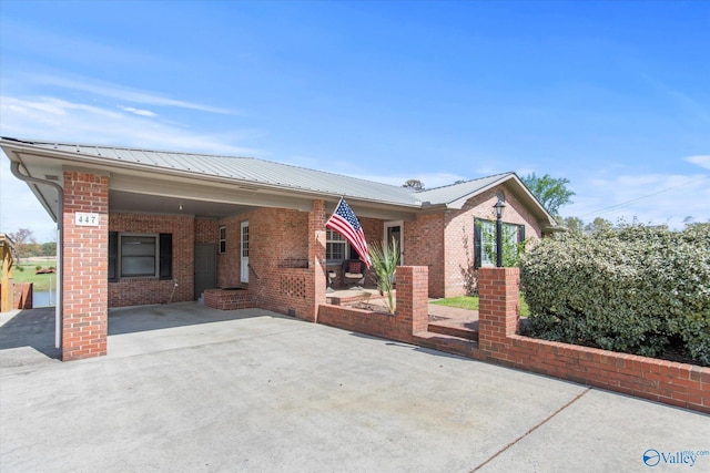 ranch-style home with metal roof, concrete driveway, brick siding, and a carport
