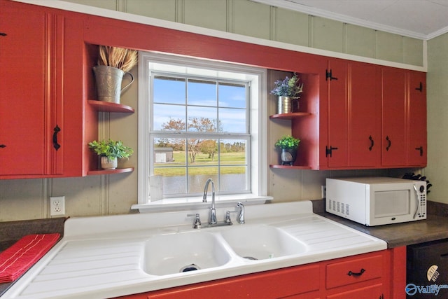 kitchen featuring white microwave, open shelves, and red cabinets