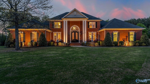 neoclassical home with brick siding and a front lawn