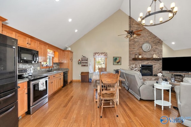 kitchen featuring high vaulted ceiling, tasteful backsplash, sink, black appliances, and a brick fireplace