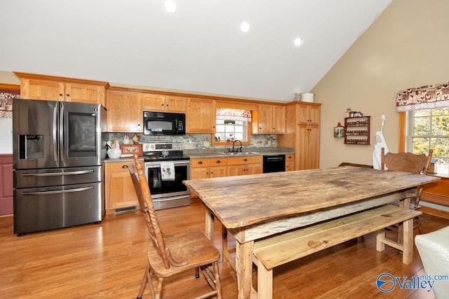 kitchen featuring sink, backsplash, high vaulted ceiling, black appliances, and light hardwood / wood-style floors