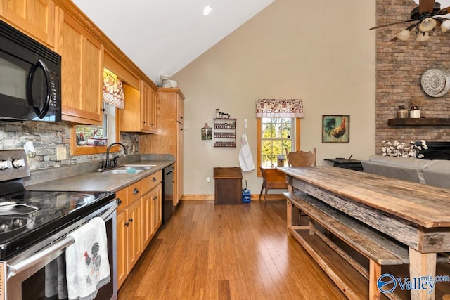 kitchen with sink, light hardwood / wood-style flooring, high vaulted ceiling, tasteful backsplash, and black appliances