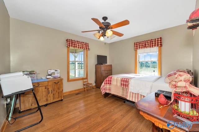 bedroom with ceiling fan, light hardwood / wood-style floors, and multiple windows