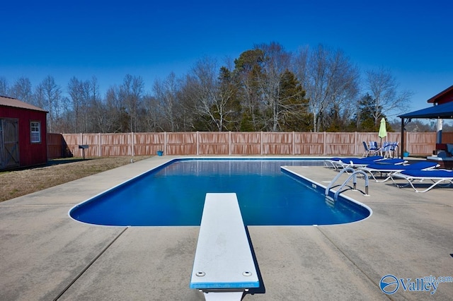 view of swimming pool featuring a patio and a diving board