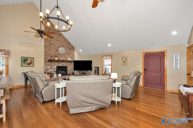 living room featuring ceiling fan, high vaulted ceiling, a brick fireplace, and light hardwood / wood-style flooring