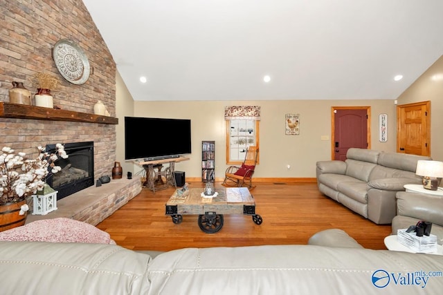 living room with vaulted ceiling, hardwood / wood-style floors, and a brick fireplace