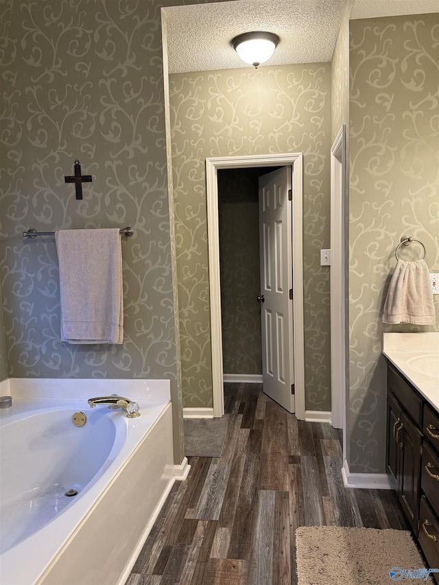 504 Sussex Dr SW, Huntsville, AL 35824 - bathroom with wallpapered walls, wood finished floors, a bath, vanity, and baseboards