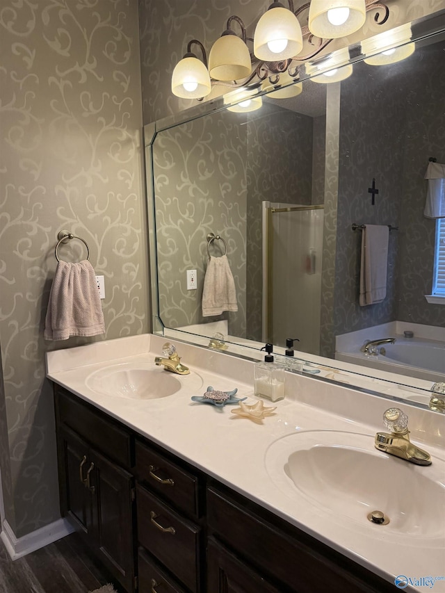 504 Sussex Dr SW, Huntsville, AL 35824 - bathroom featuring wallpapered walls, double vanity, a tub to relax in, and wood finished floors
