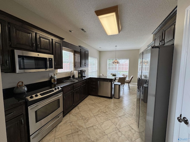 504 Sussex Dr SW, Huntsville, AL 35824 - kitchen with stainless steel appliances, a sink, a textured ceiling, dark countertops, and pendant lighting