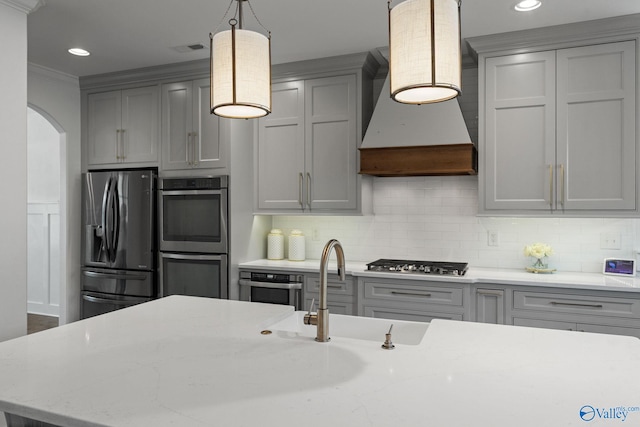 kitchen with custom range hood, gray cabinetry, stainless steel appliances, and hanging light fixtures