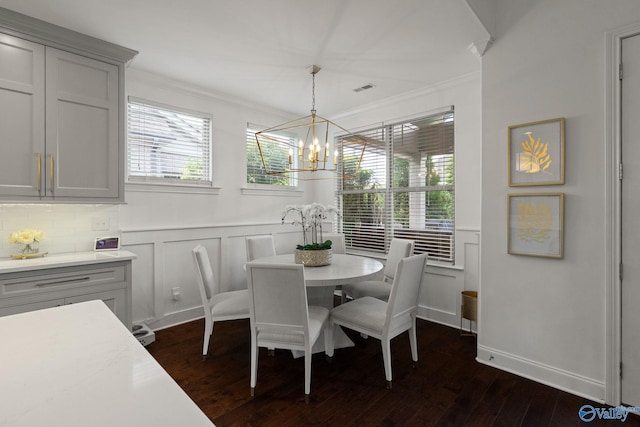 dining area featuring an inviting chandelier, ornamental molding, and dark wood-type flooring