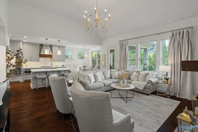 living room with vaulted ceiling, a notable chandelier, dark hardwood / wood-style flooring, and a healthy amount of sunlight