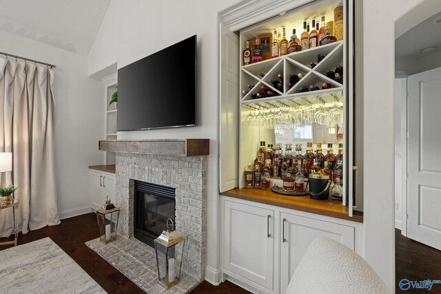 living room featuring a stone fireplace, high vaulted ceiling, built in features, and a notable chandelier