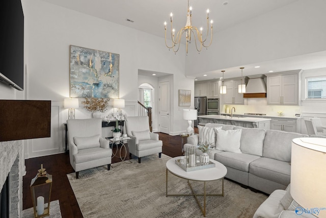 living room featuring a brick fireplace, an inviting chandelier, hardwood / wood-style floors, and a high ceiling