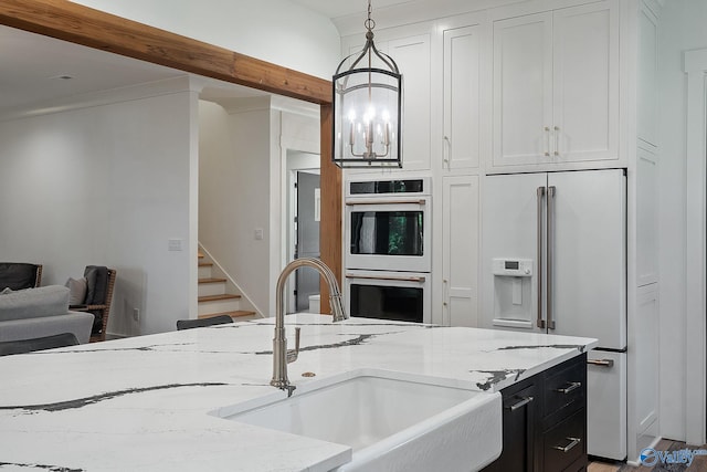 kitchen featuring white built in fridge, double oven, light stone countertops, and hanging light fixtures